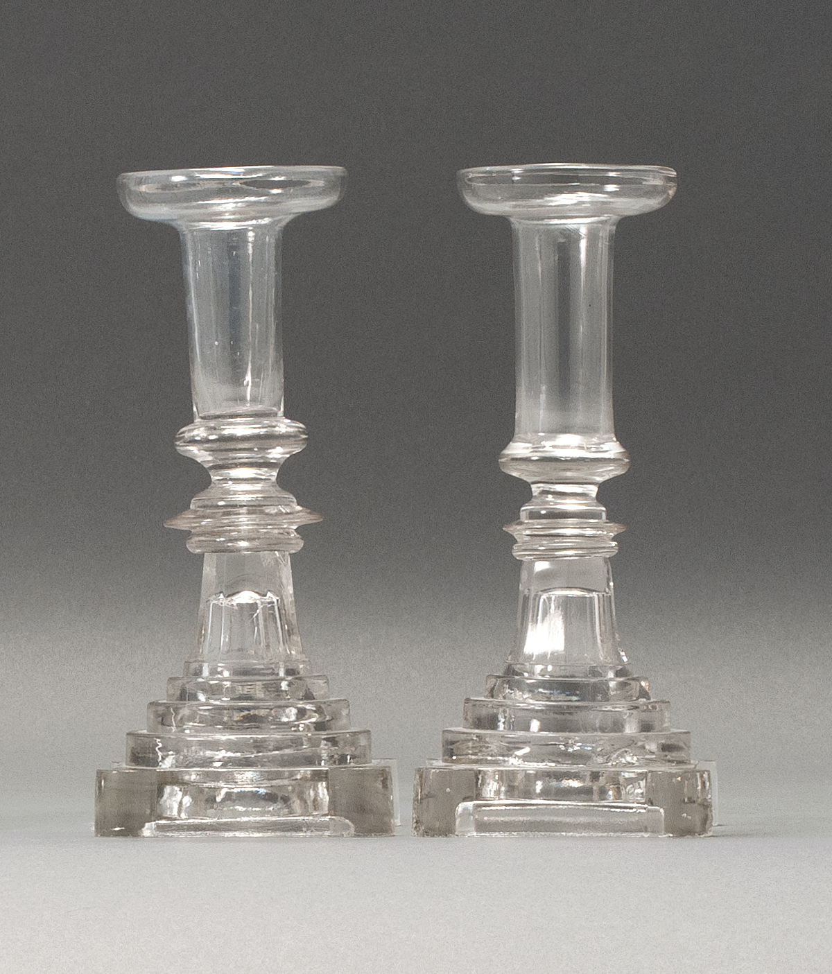 Appraisal: PAIR OF SANDWICH GLASS COMPANY CLEAR GLASS CANDLESTICKS Second Quarter