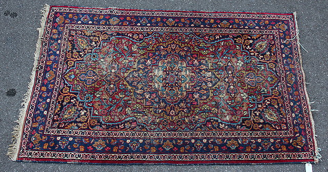 Appraisal: AN OLD ORIENTAL RED GROUND RUG with floral geometric designs