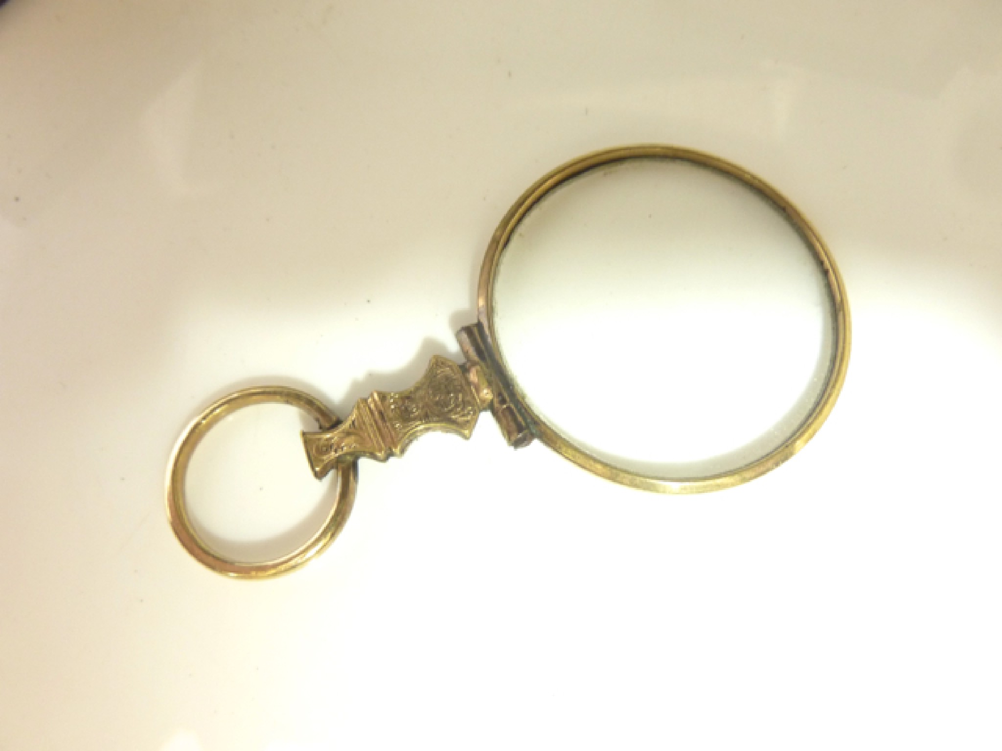 Appraisal: A Victorian gold-plated magnifying glass with scrolling details accompanied by