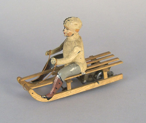 Appraisal: Tin wind-up boy seated on a sled late th c