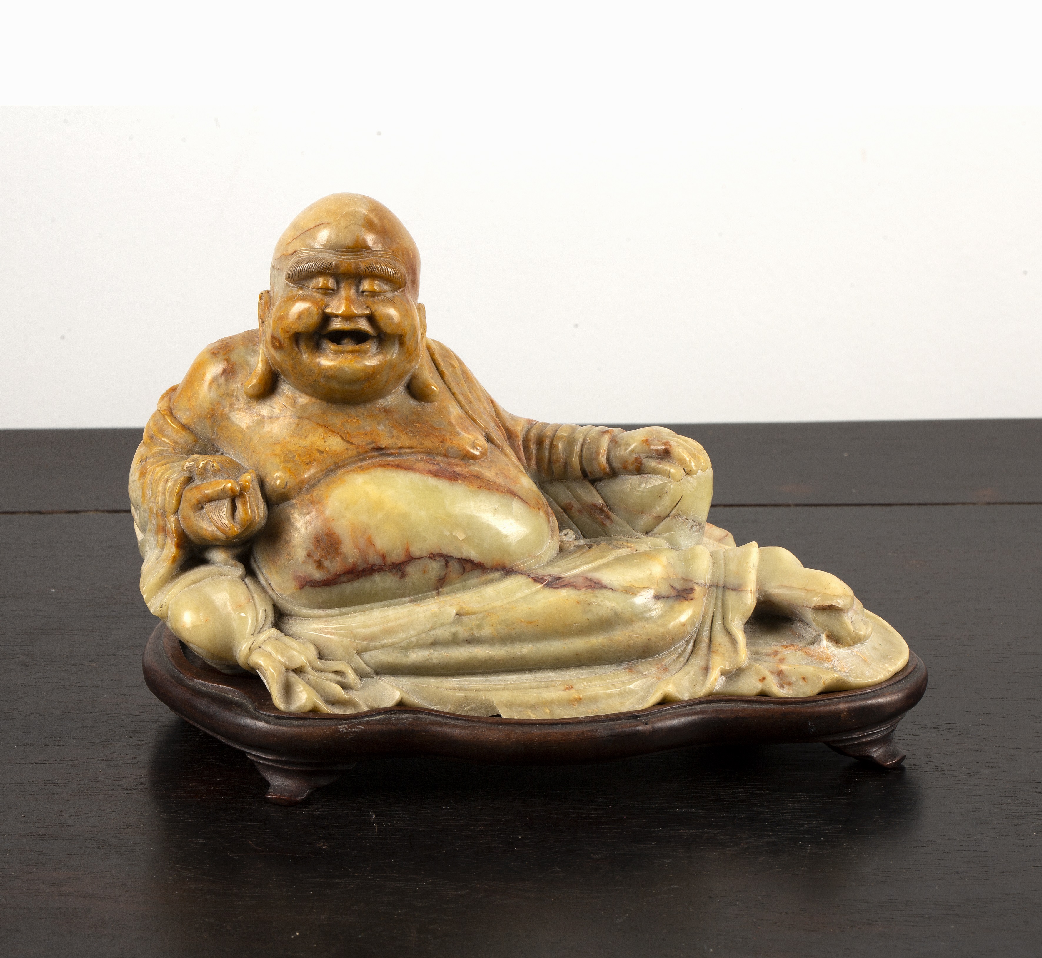 Appraisal: Reclining soapstone buddhaChinese early th Century the figure holding a