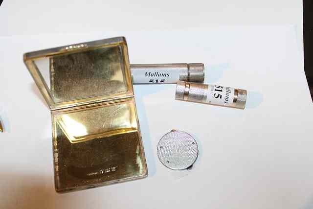 Appraisal: A SQUARE SILVER COMPACT with engine turned decoration and gold