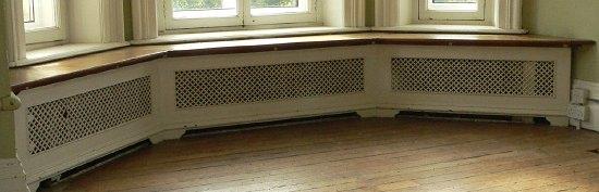 Appraisal: A triple panelled pierced cast radiator surround with wooden top