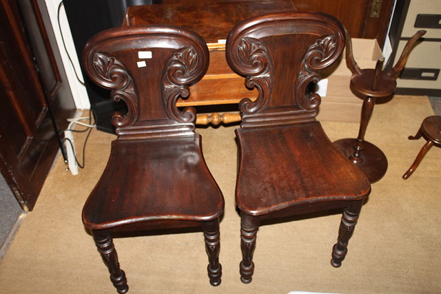 Appraisal: A PAIR OF VICTORIAN MAHOGANY HALL CHAIRS with carved backs