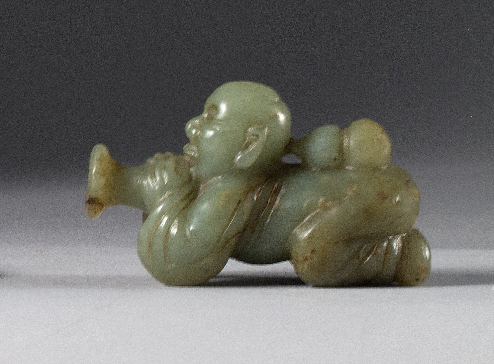 Appraisal: CELADON JADE FIGURE th CenturyDepicting a reclining figure playing a