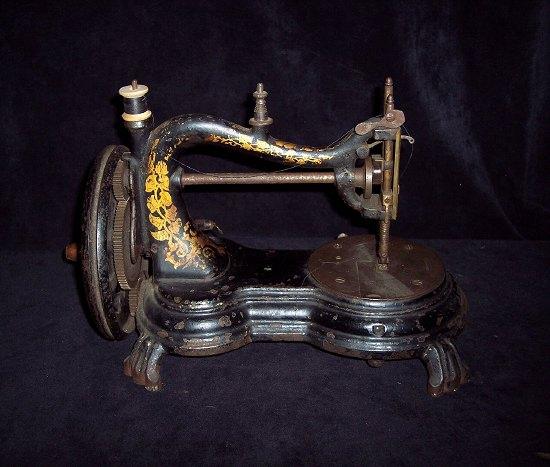 Appraisal: A sewing machine with gilded decoration and turned wood handle