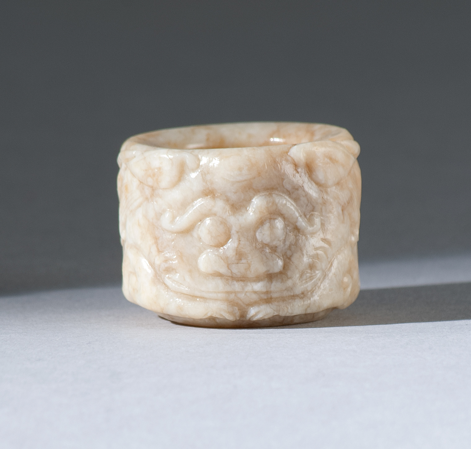 Appraisal: CHICKEN-BONE JADE THUMB RING th CenturyWith dramatic guardian lion carving