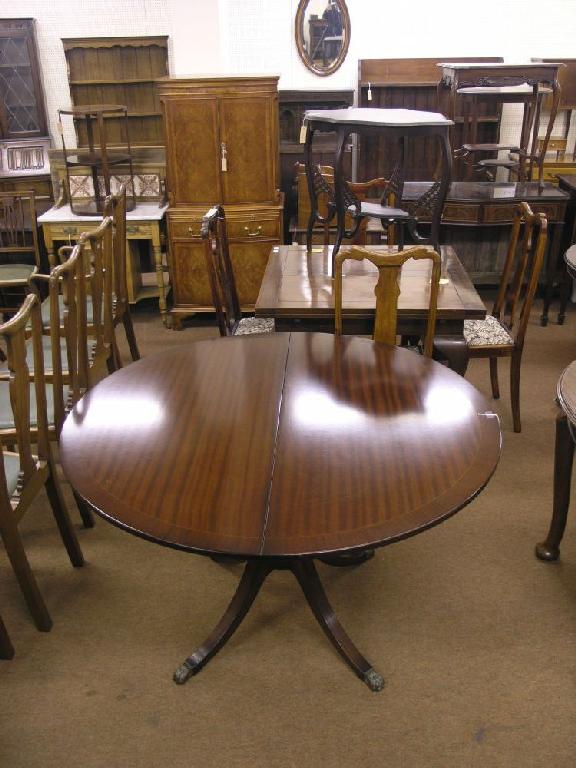 Appraisal: A reproduction circular mahogany dining table with extra leaf cross-banded