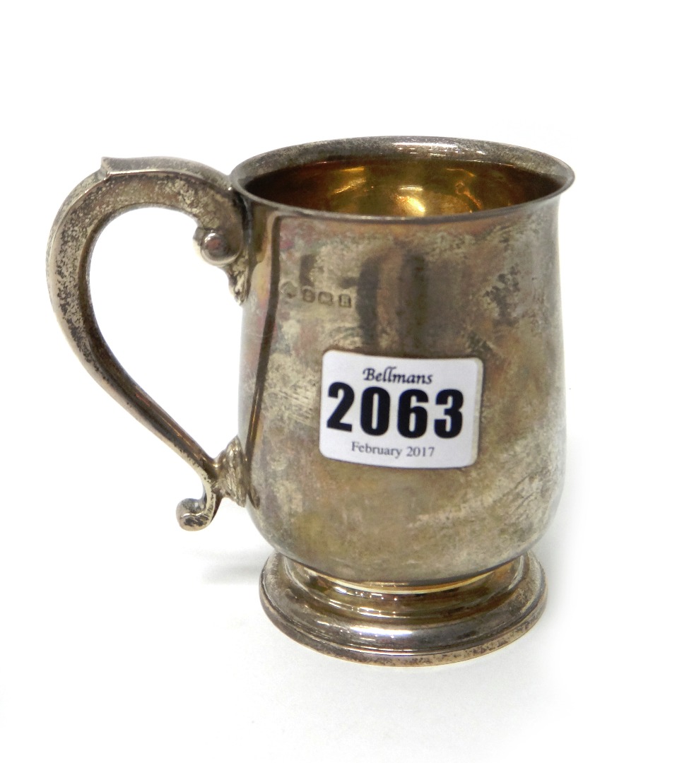 Appraisal: A silver baluster shaped mug with a scrolling handle raised