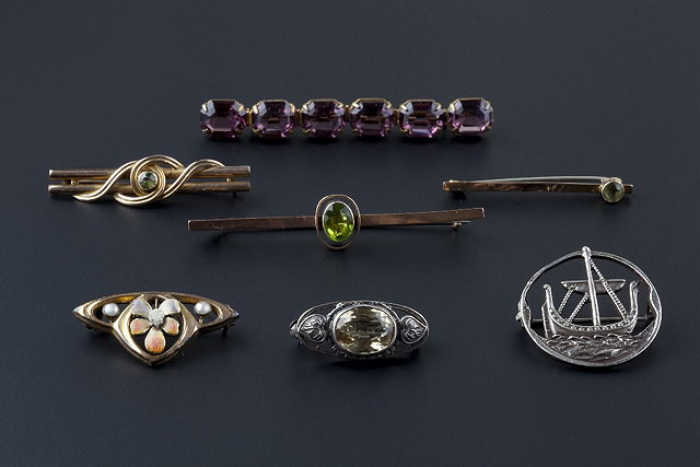 Appraisal: A collection of brooches comprising a peridot set bar brooch