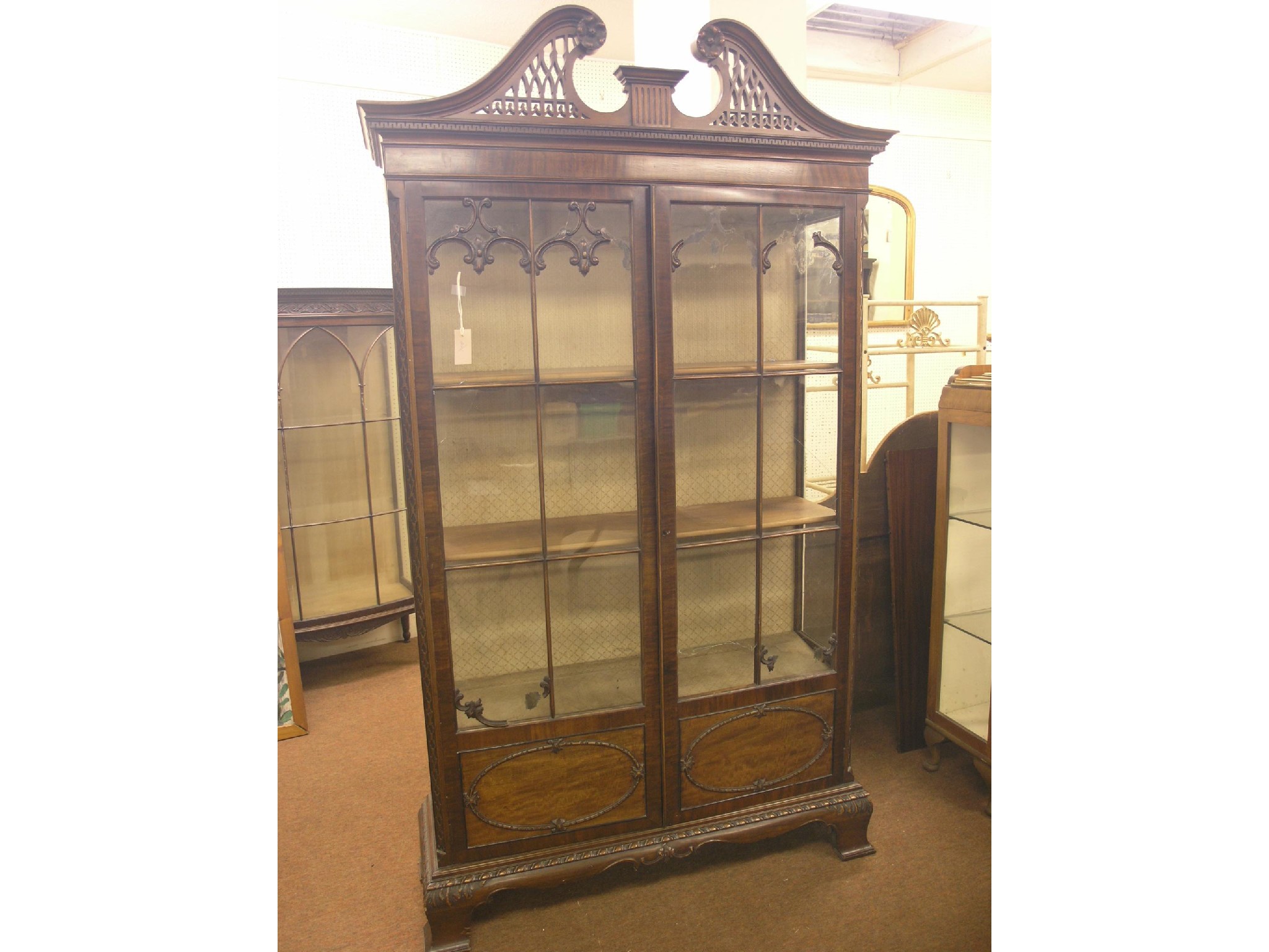 Appraisal: A Chippendale-style mahogany display cabinet pierced swan-neck pediment above a