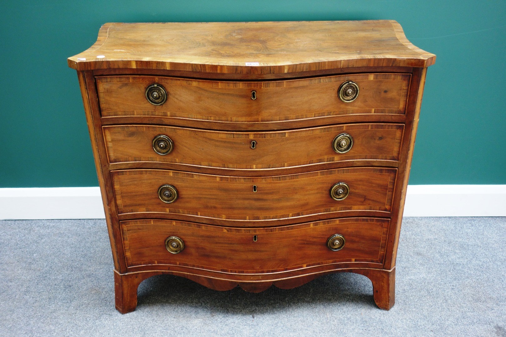 Appraisal: A George III inlaid cross-banded mahogany serpentine chest the top