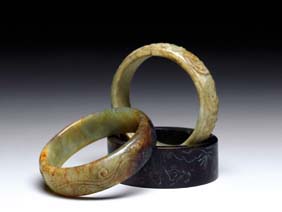 Appraisal: THREE JADE AND HARDSTONE BANGLES Three Chinese carved jade and