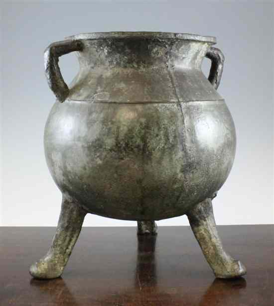 Appraisal: A large bronze cauldron on three legs with projecting side