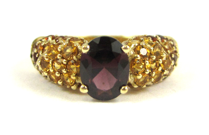 Appraisal: GARNET AND FOURTEEN KARAT GOLD RING featuring an oval-cut garnet