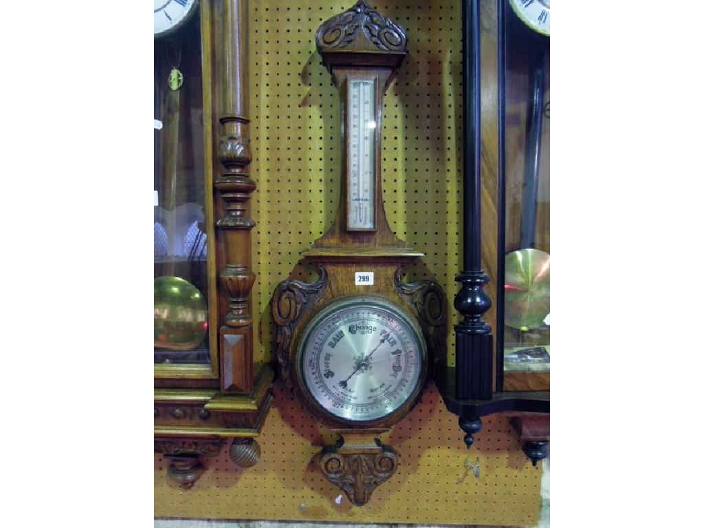 Appraisal: An Edwardian oak aneroid barometer with silvered dials and carved