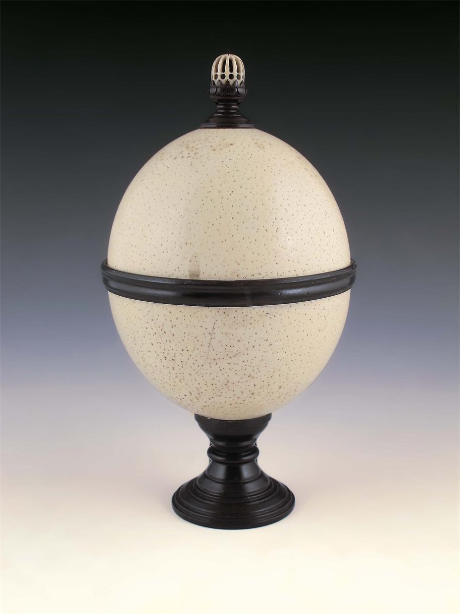 Appraisal: An ebonised mounted ostrich egg cup and cover