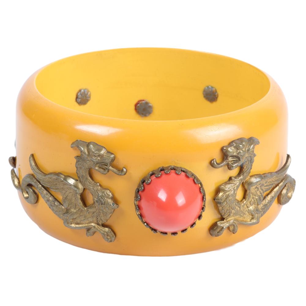 Appraisal: WIDE BAKELITE BANGLE WITH APPLIED GILT DRAGONS AND CORAL DOMED