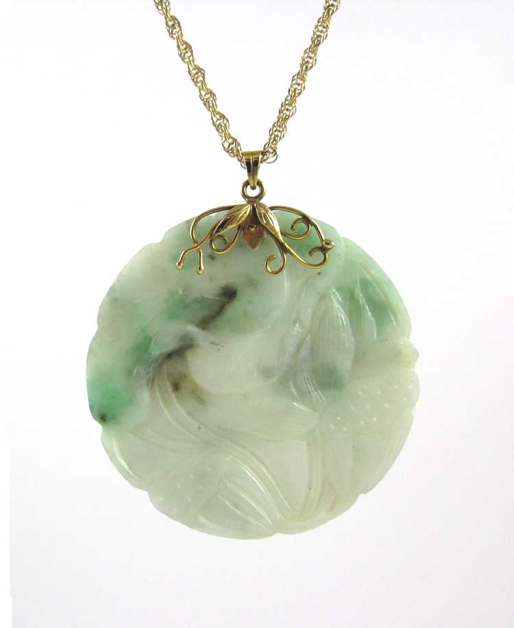 Appraisal: CHINESE CARVED JADE PENDANT AND GOLD CHAIN a round multi-shade