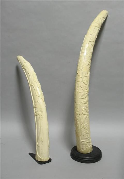 Appraisal: TWO SIMILARLY CARVED IVORY TUSKS Carved with African villagers with