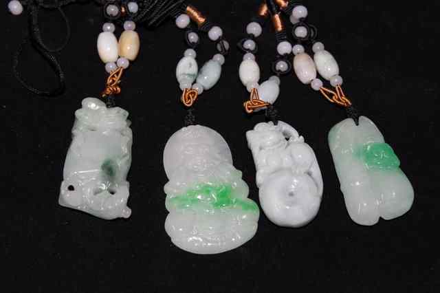 Appraisal: FOUR ORIENTAL JADE PENDANTS each hanging from a black cord