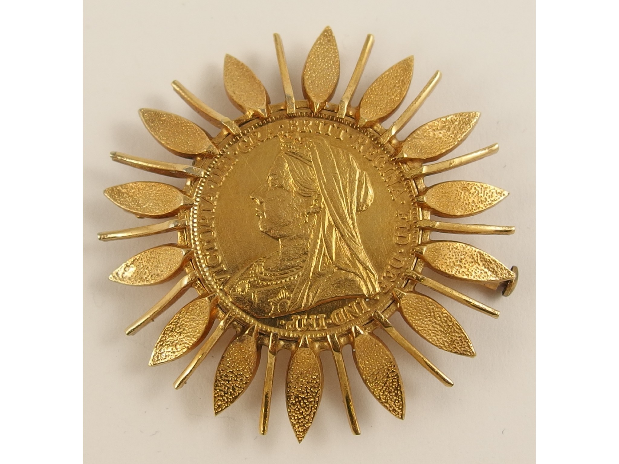 Appraisal: A faux sovereign in a yellow metal sunburst brooch mount