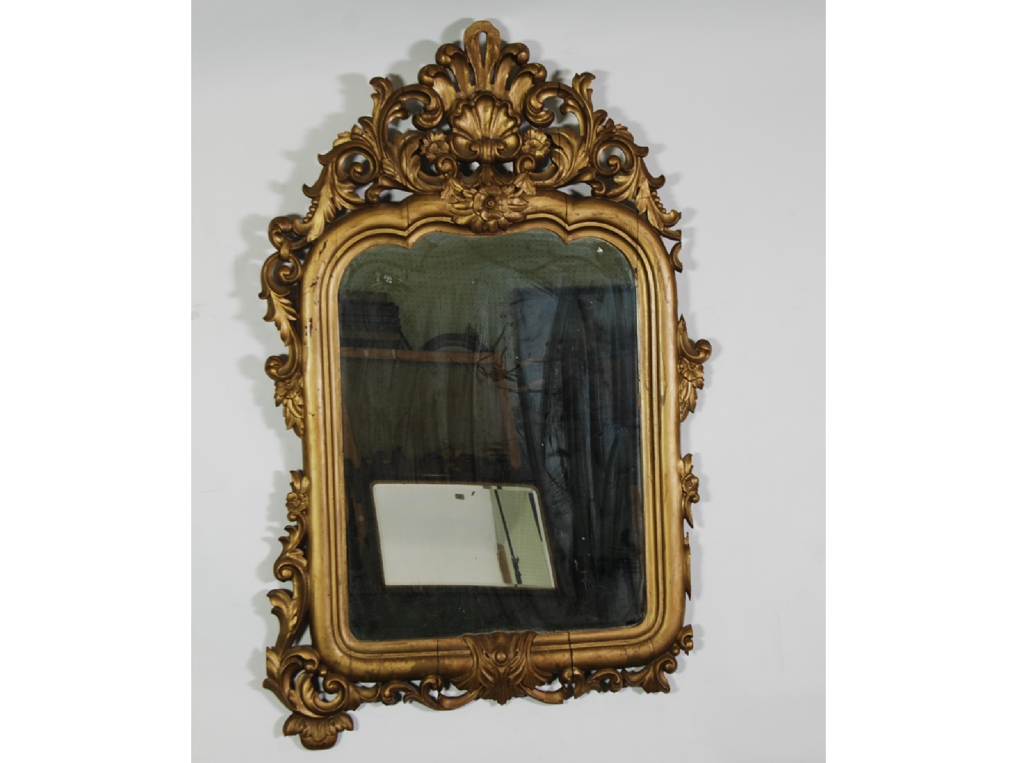 Appraisal: A ROCOCO GILTWOOD WALL MIRROR the shaped oblong plate within