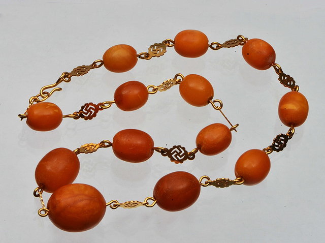 Appraisal: A GRADUATED AMBER BEAD NECKLACE linked with gilt metal links