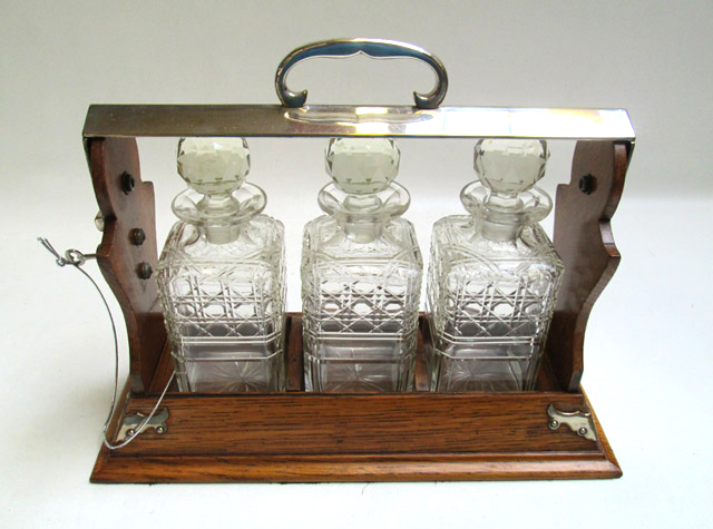 Appraisal: ENGLISH TANTALUS SET of three cut crystal decanters the wood