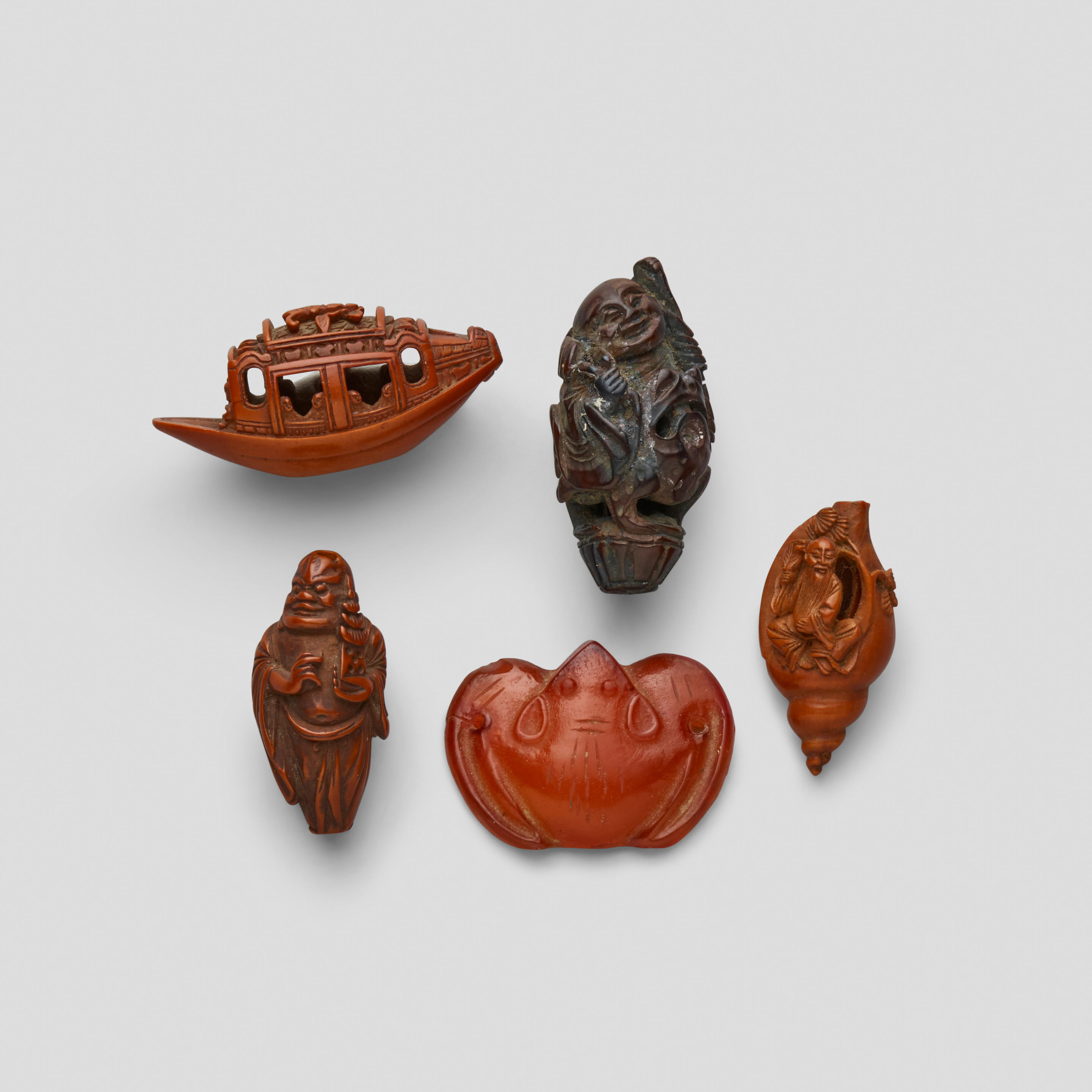 Appraisal: FOUR SEED CARVINGS AND ONE SMALL CARNELIAN PENDANT The first