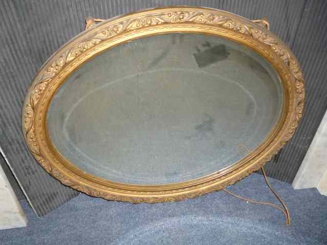 Appraisal: AN OVAL GILT FRAMED WALL MIRROR with bevelled glass wide