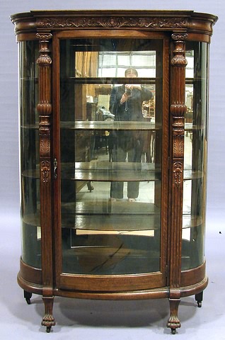 Appraisal: Cresting with carved leaf scroll swell-front glazed door flanked by