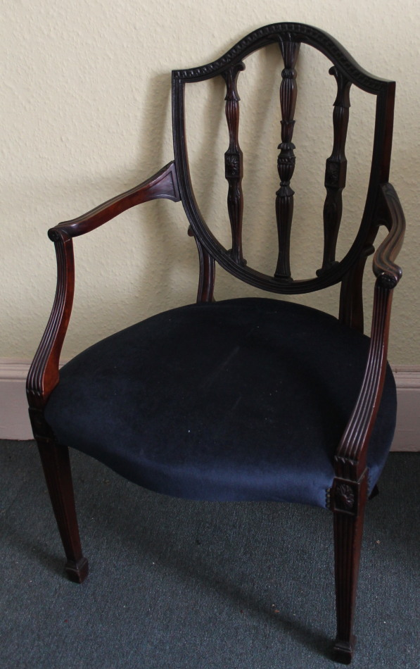 Appraisal: A mahogany open arm chair in Sheraton style the shield