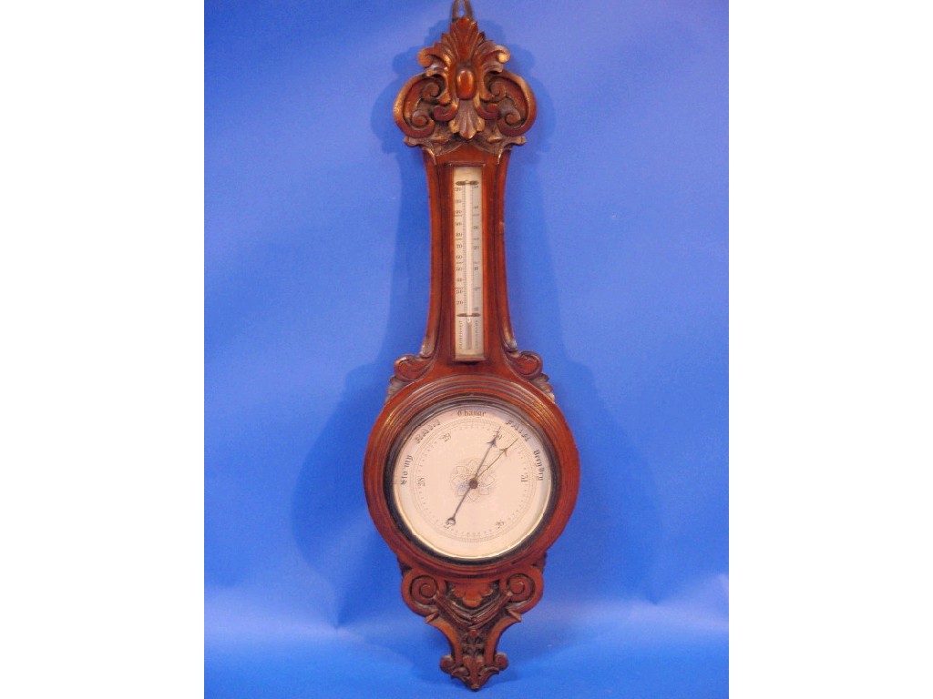 Appraisal: An Edwardian carved oak cased aneroid barometer with a thermometer