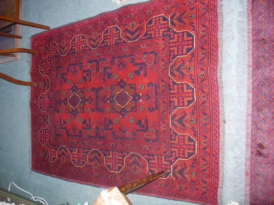 Appraisal: A RED GROUND RUG with geometric designs and panel decoration