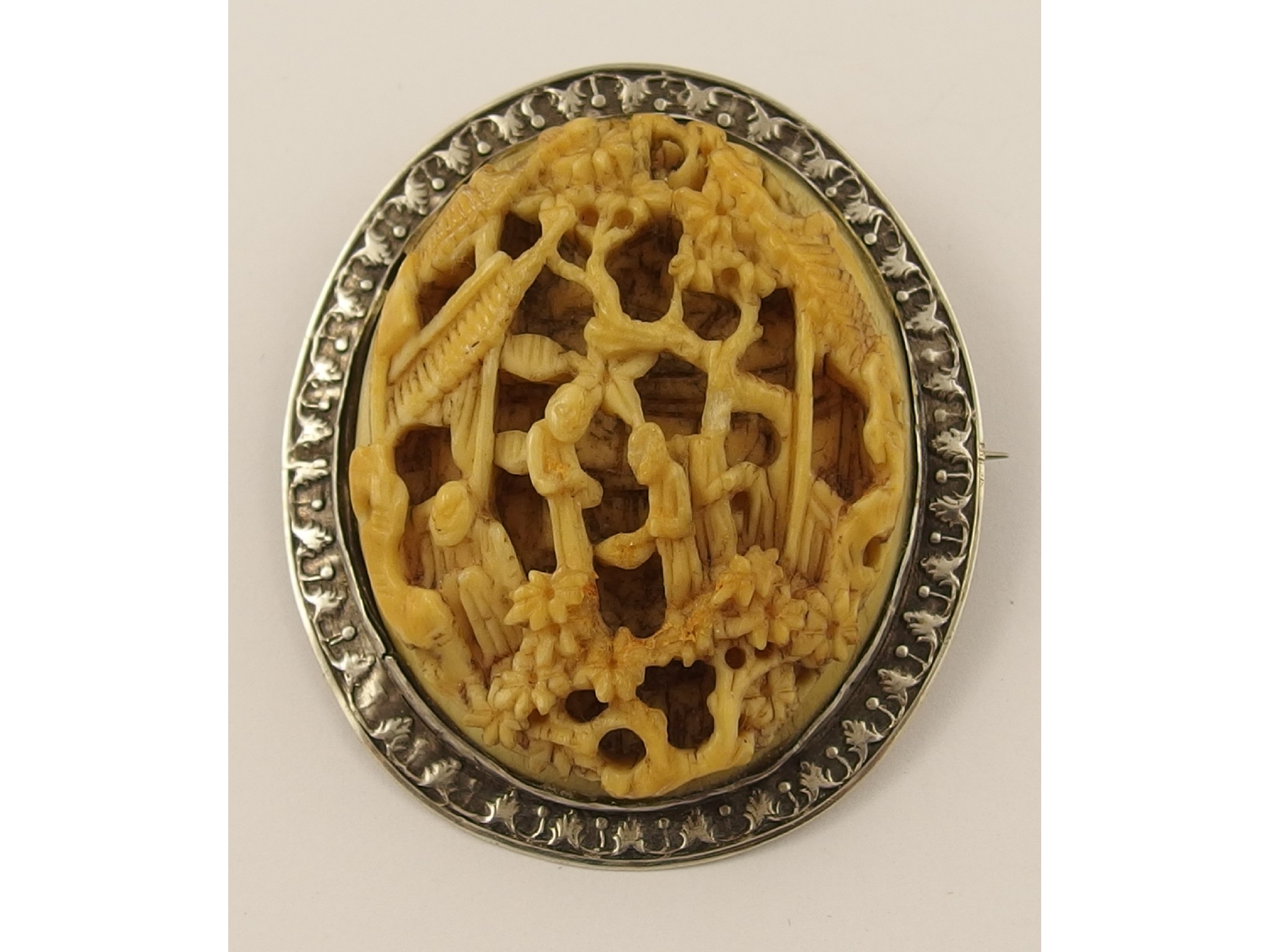 Appraisal: A white metal mounted carved bone oriental brooch