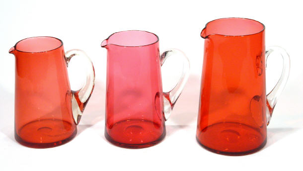 Appraisal: Graduated set of three Victorian cranberry glass jugs largest cm