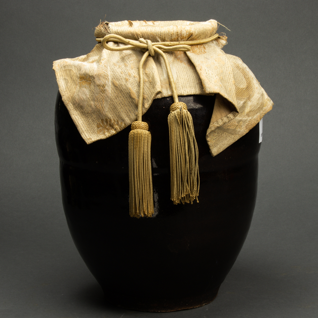 Appraisal: Japanese brown glazed stoneware jar with silk cover height