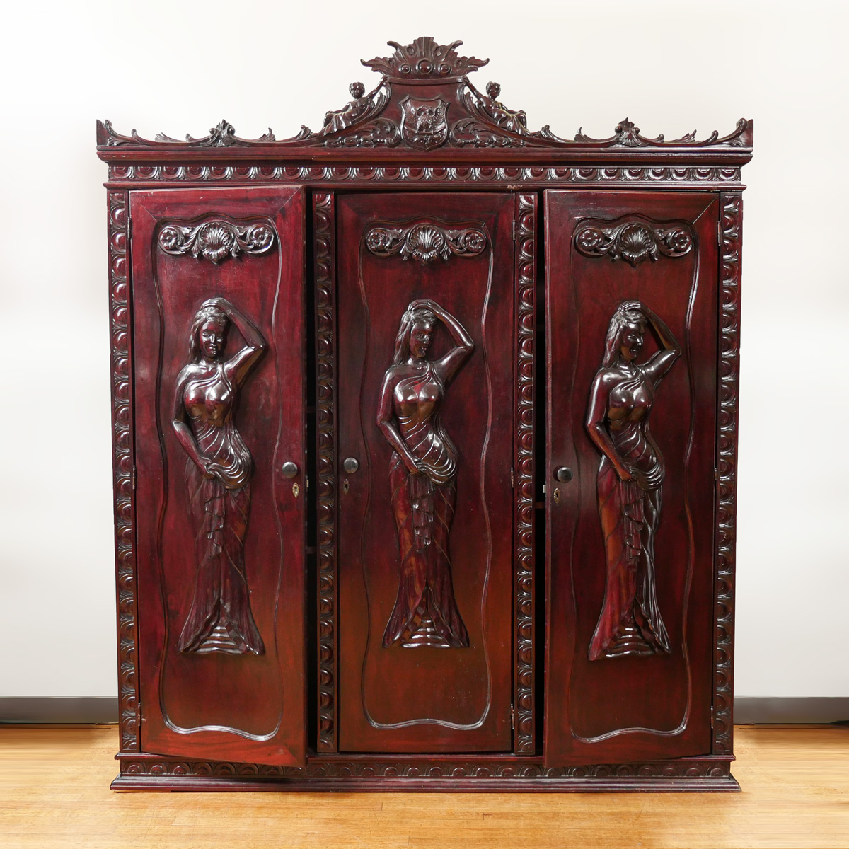 Appraisal: CARVED MAHOGANY THREE DOOR ARMOIRE Having a scrolling foliate designed