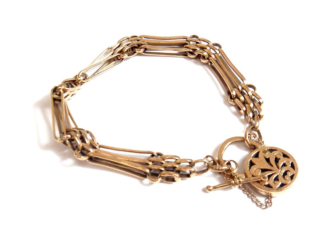 Appraisal: A gold bar and oval link gate bracelet on a