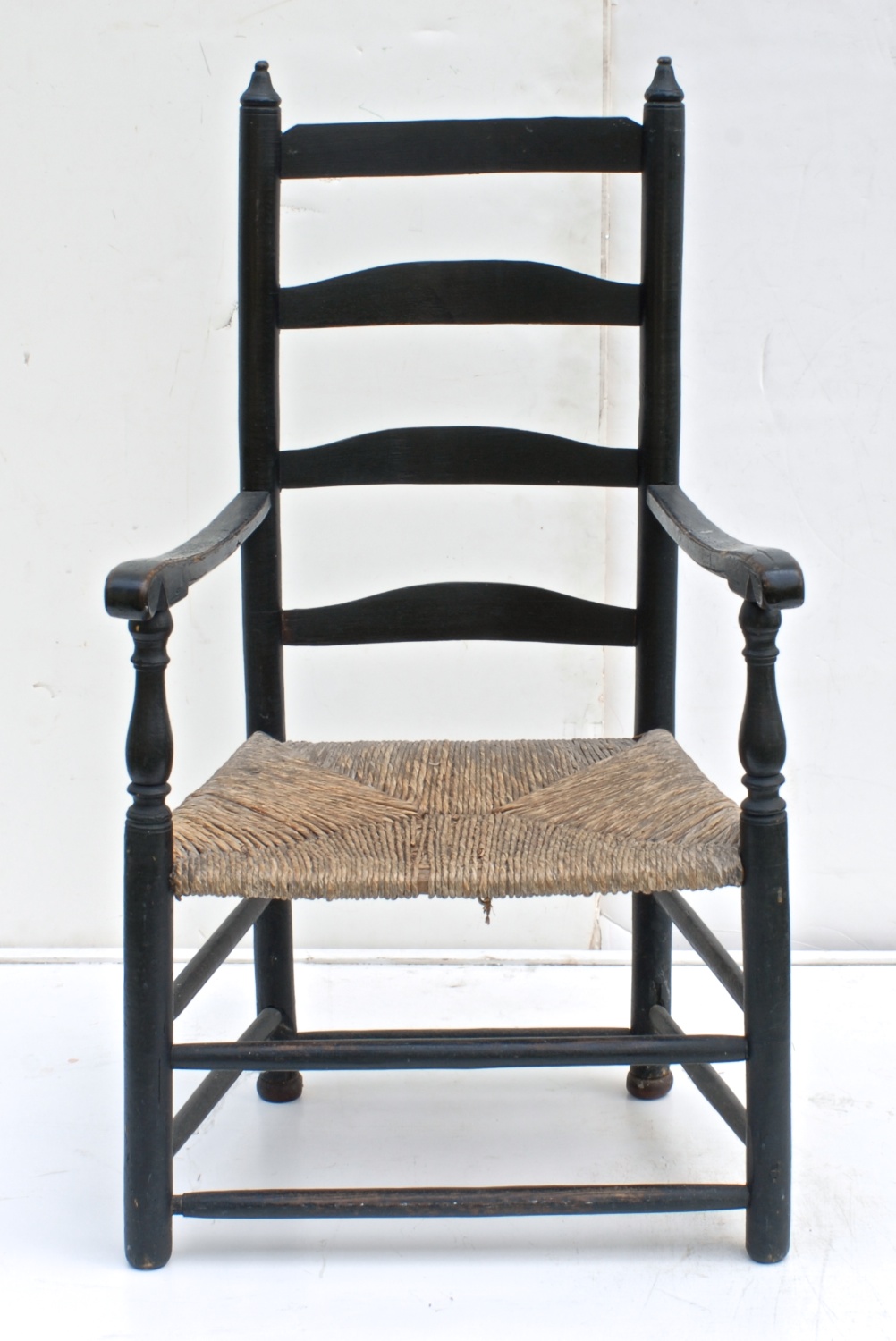 Appraisal: TH CENTURY AMERICAN LADDERBACK RUSH-SEAT ARMCHAIR in black paint Four