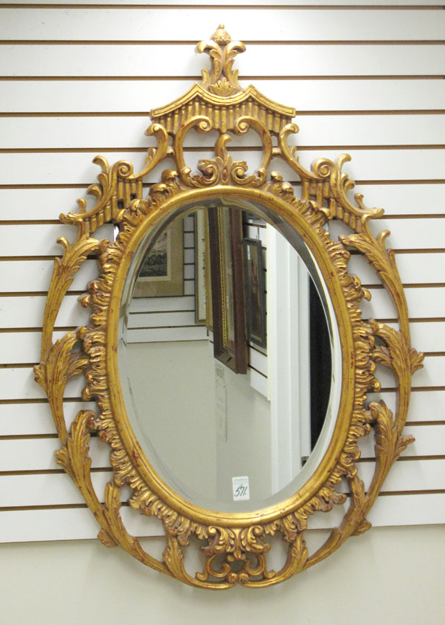 Appraisal: A BEVELED OVAL WALL MIRROR inset in a molded light-weight