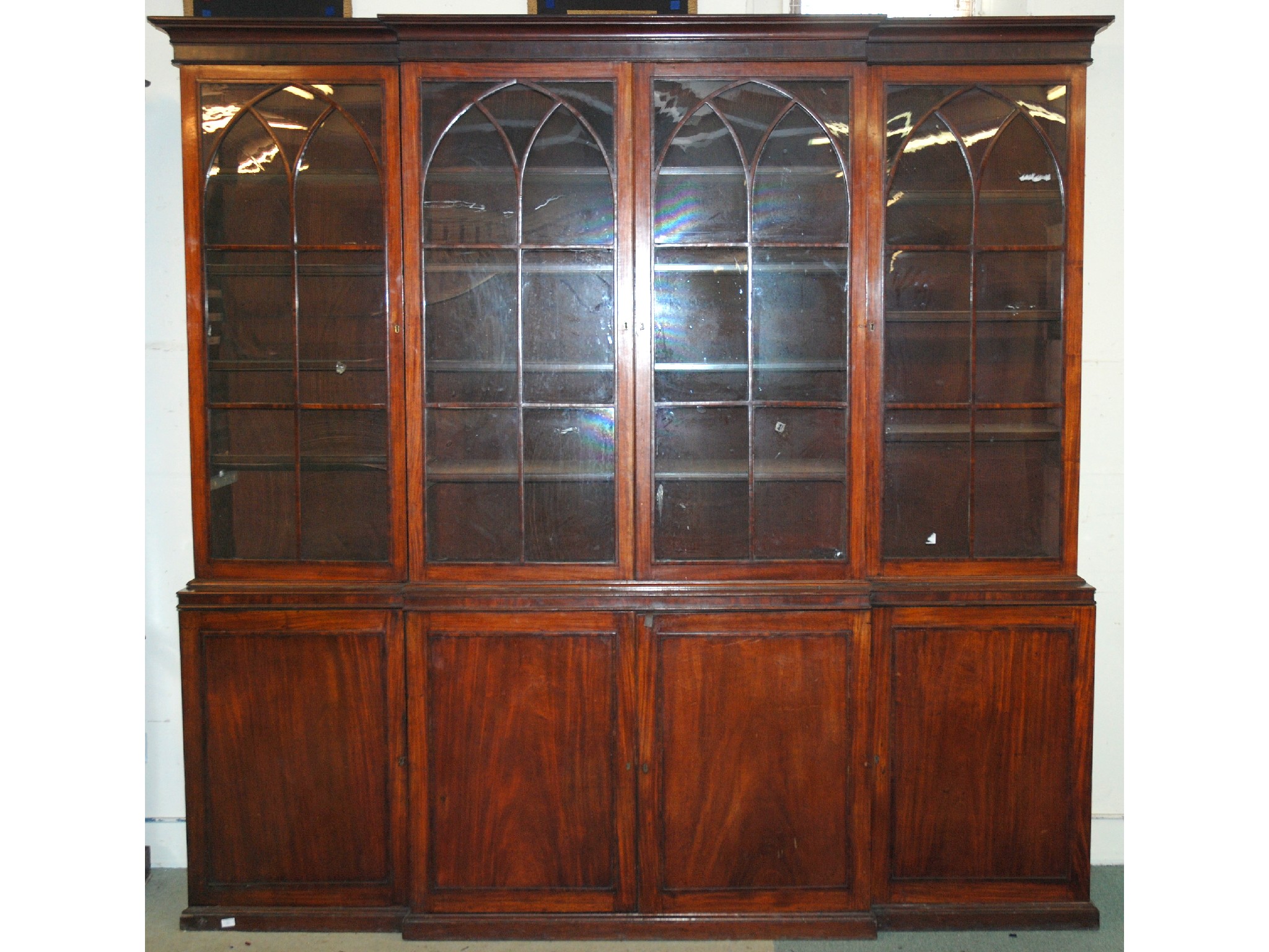 Appraisal: A th Century mahogany breakfront bookcasethe moulded over-hanging cornice above