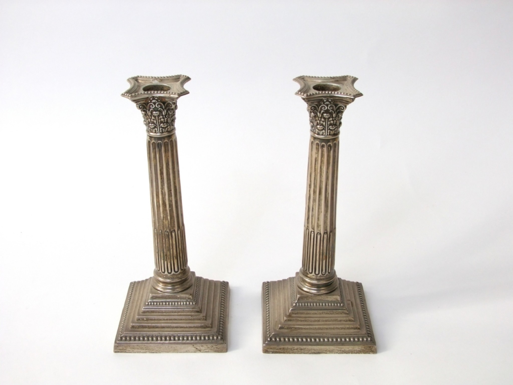 Appraisal: A pair of silver Corinthian column candlesticks raised on reeded