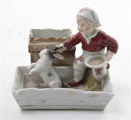 Appraisal: A German Porcelain Figural Matchstrike depicting a child clutching a