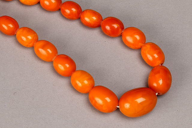 Appraisal: A GRADUATED OVAL AMBER BEAD NECKLACE dark egg yolk in