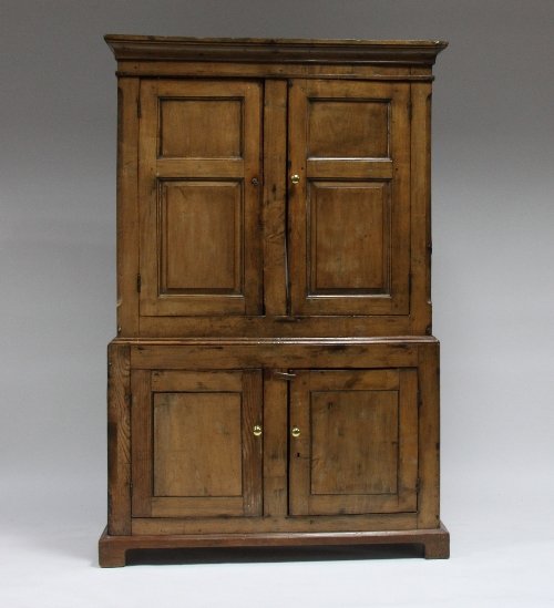 Appraisal: A fruitwood cupboard with two double-panelled doors above two further