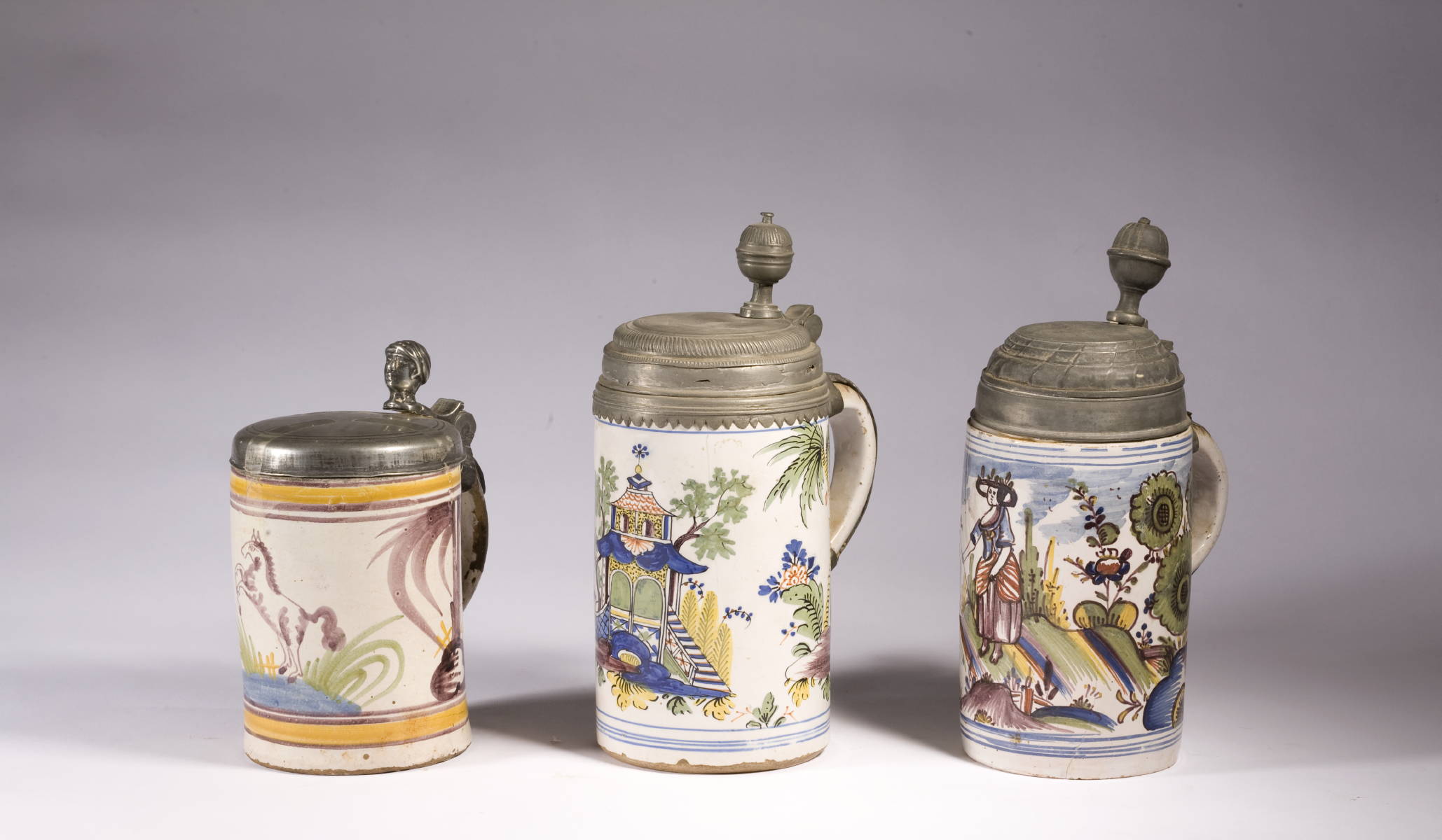 Appraisal: THREE CONTINENTAL FAIENCE MUGS WITH POLYCHROME DECORATION AND PEWTER LIDS