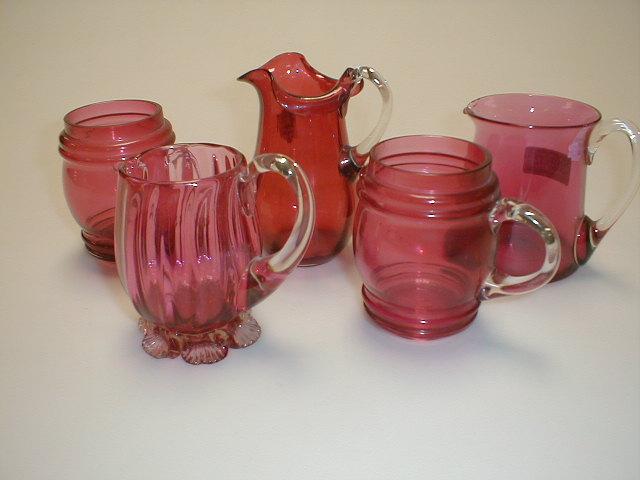 Appraisal: Three cranberry glass small jugs each with clear glass handles