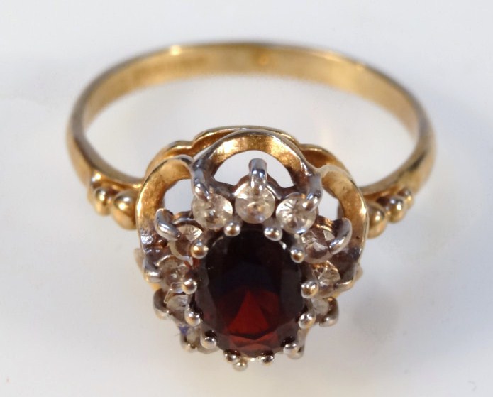 Appraisal: A cluster ring claw set with a central garnet surrounded